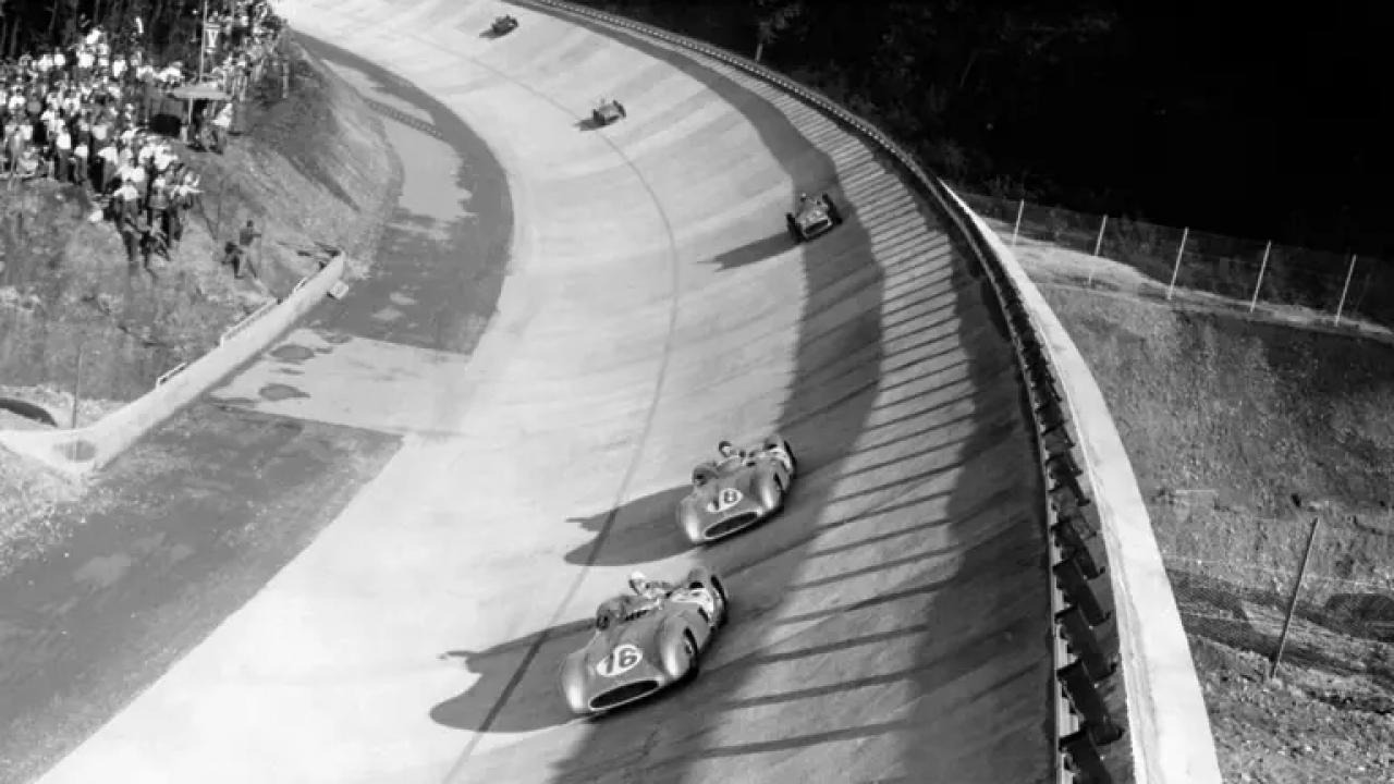 Stirling Moss i ledelsen på bankingen på Monza i 1955, med Fangio hakk i hæl.