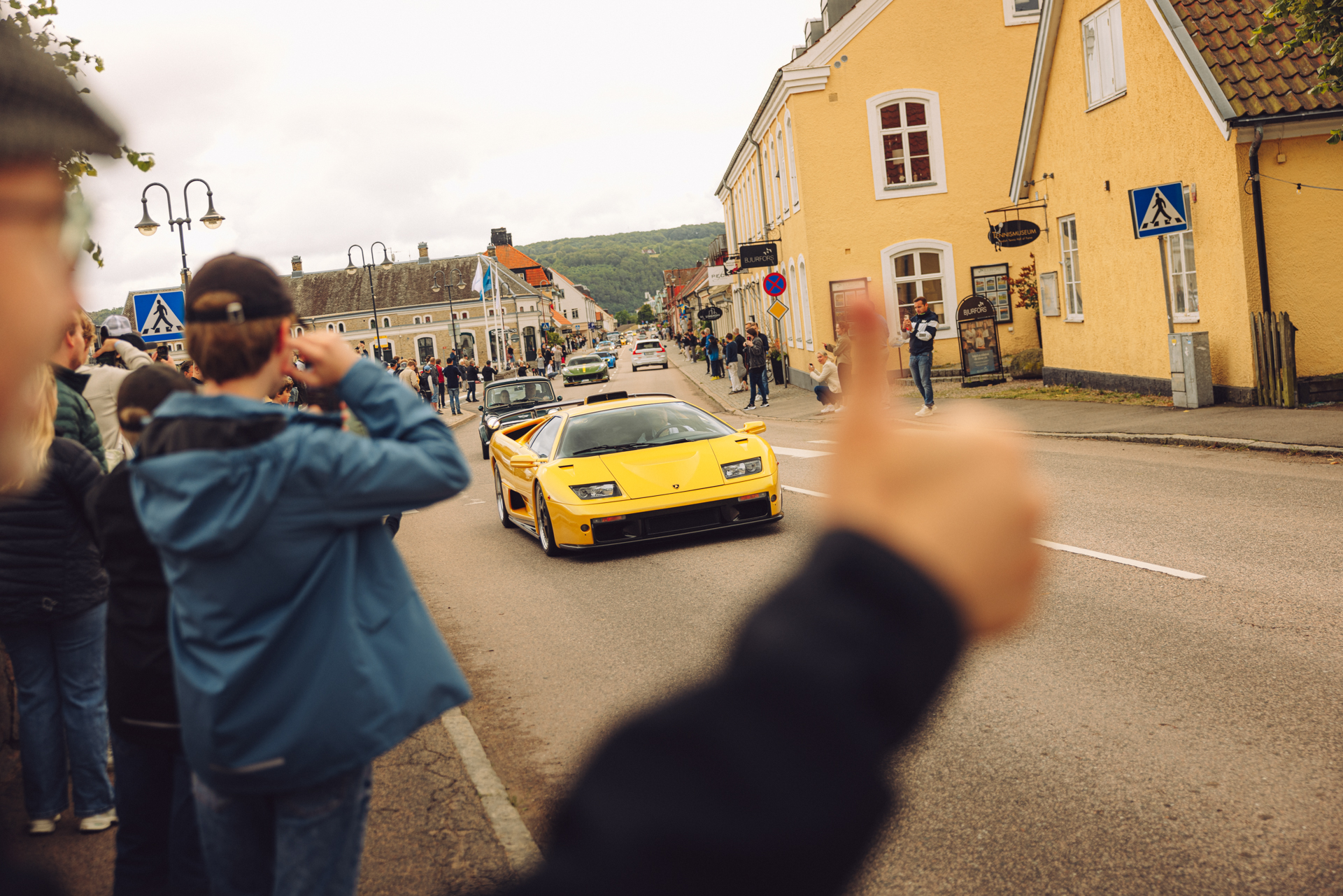 Folk stimler sammen langs gatene i Båstad når superbilene passerer på vei til eventet. 